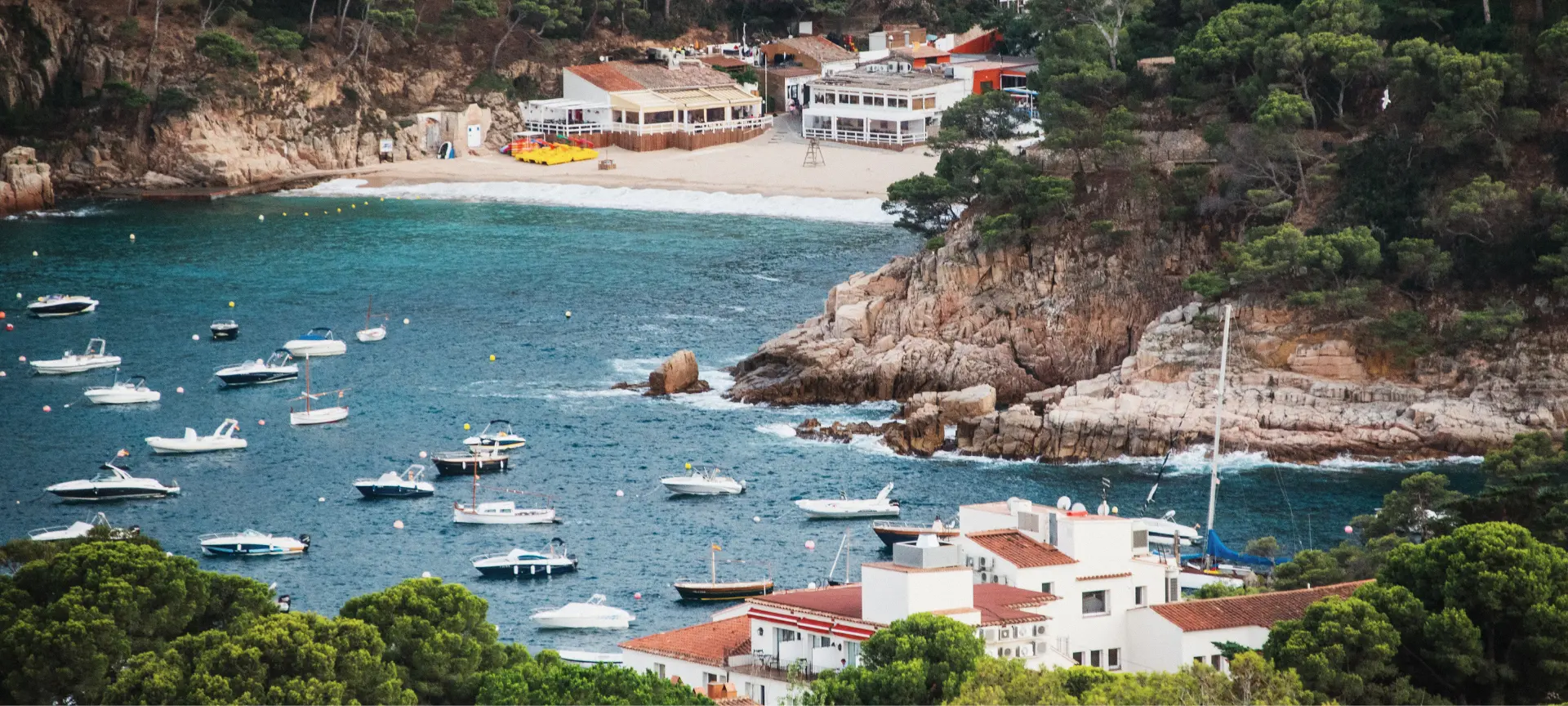 Aerial view of Cala Aiguablava with crystal-clear waters, anchored boats, and a natural setting that captures the essence of the Costa Brava.